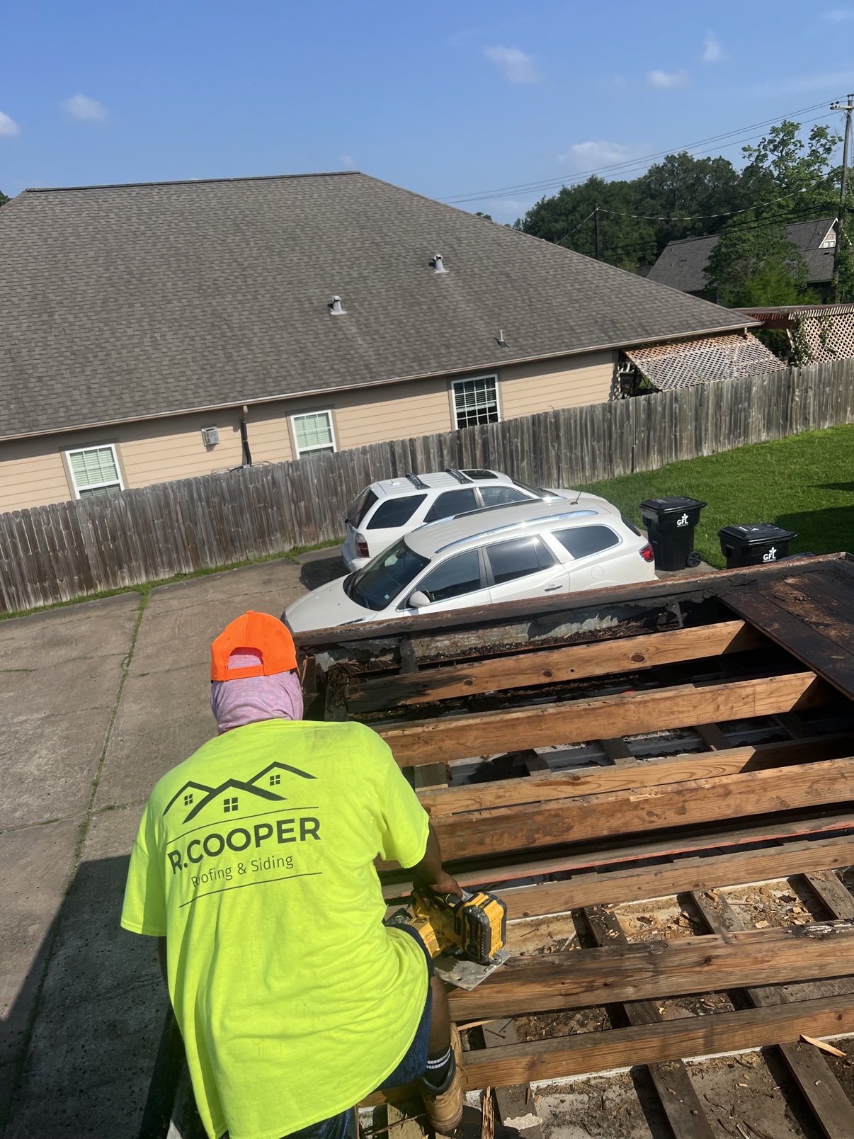 R. Cooper Roofing and Siding crew member in branded shirt during a roof tear-off