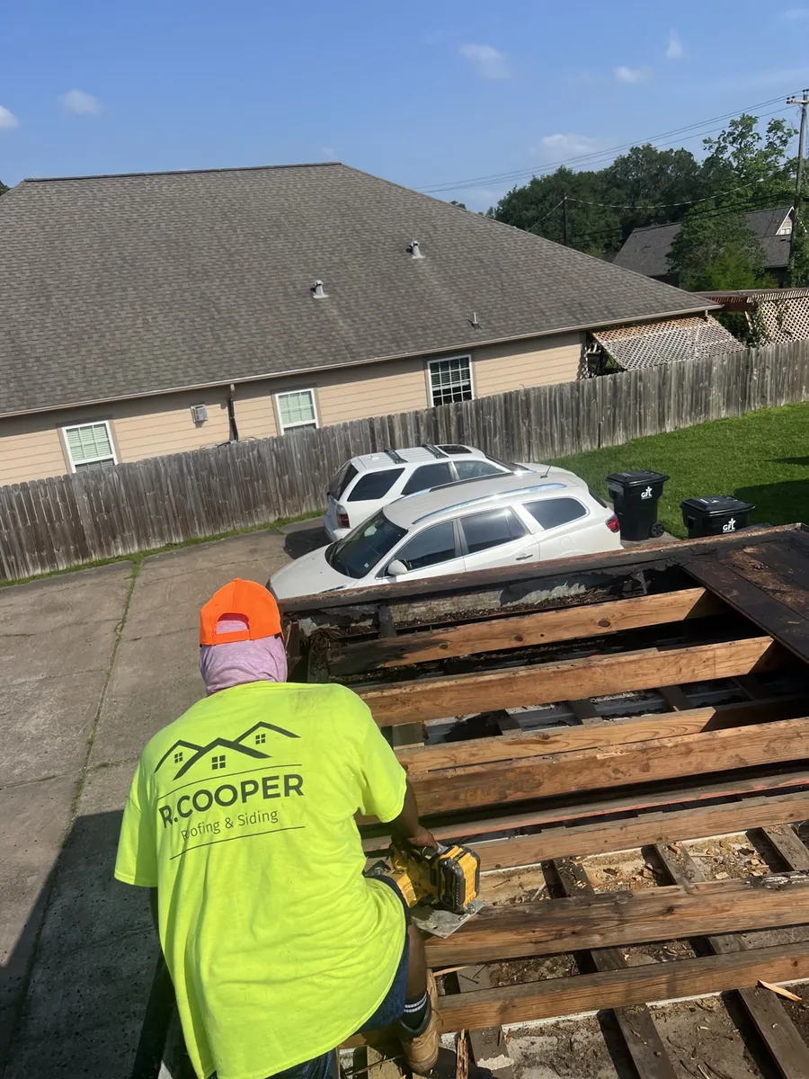 R. Cooper Roofing and Siding crew member in branded shirt during a roof tear-off